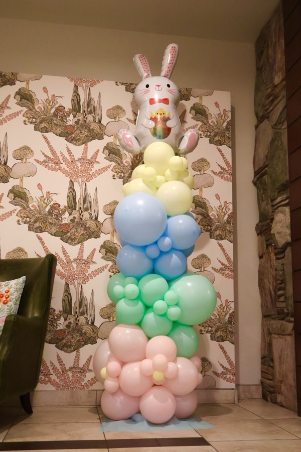 Pastel balloon column topped with a bunny in front of a botanical backdrop by AZ Party Mart
