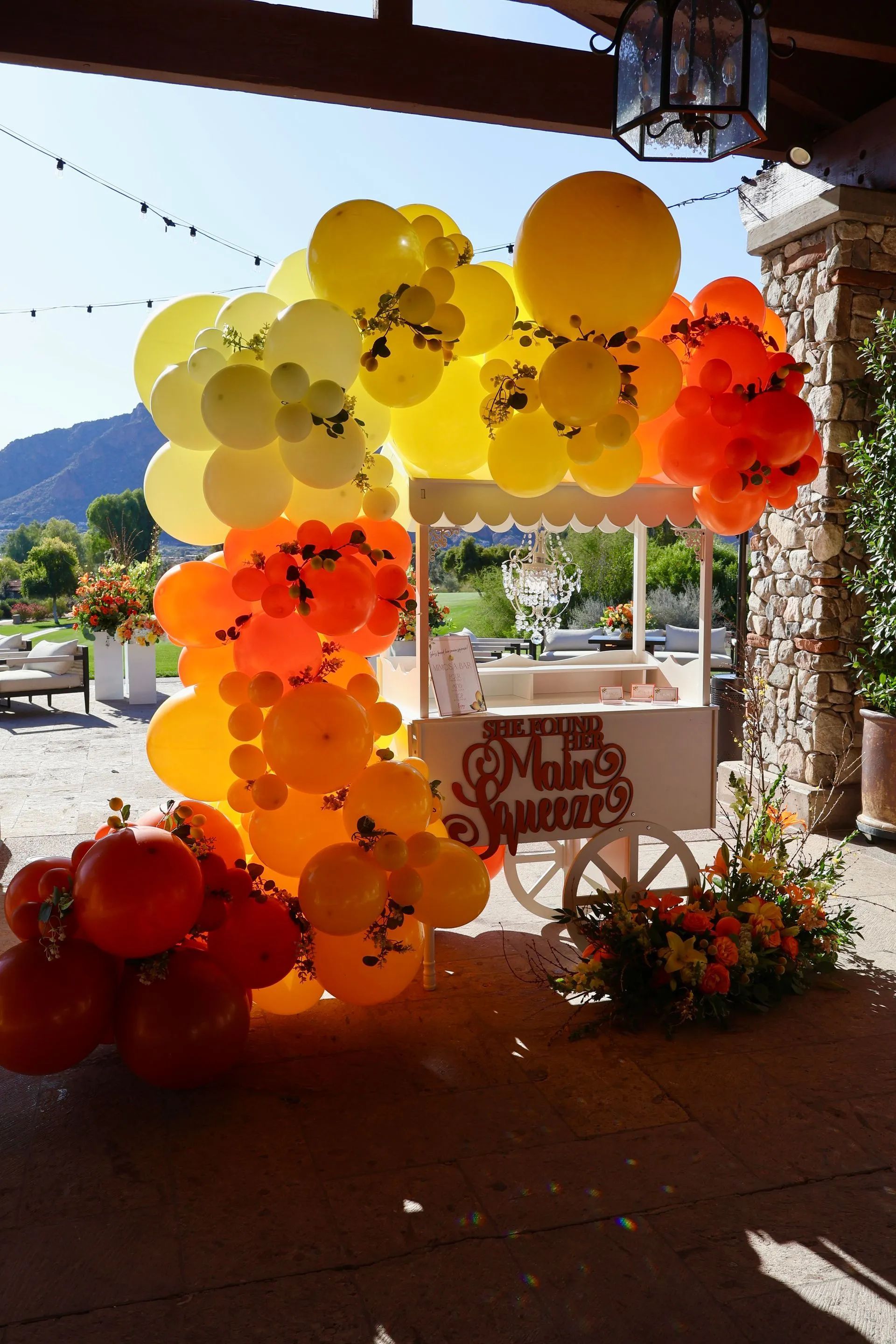 Yellow, orange, red outdoor balloon arch with mountain backdrop