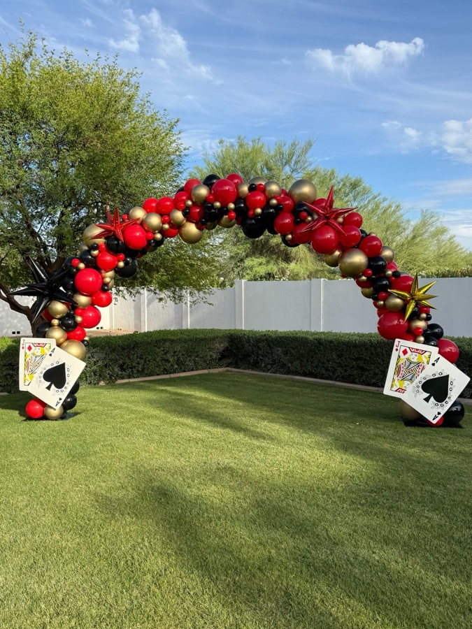Red, black and white casino balloon arch with giant playing cards by AZ Party Mart