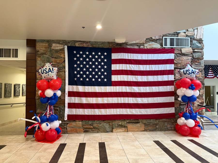 Patriotic red, white and blue balloon columns beside a large flag by AZ Party Mart