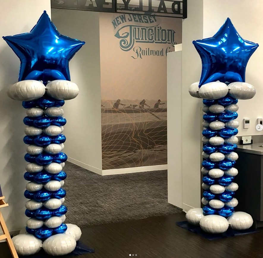 Navy and silver balloon columns topped with blue foil stars by AZ Party Mart