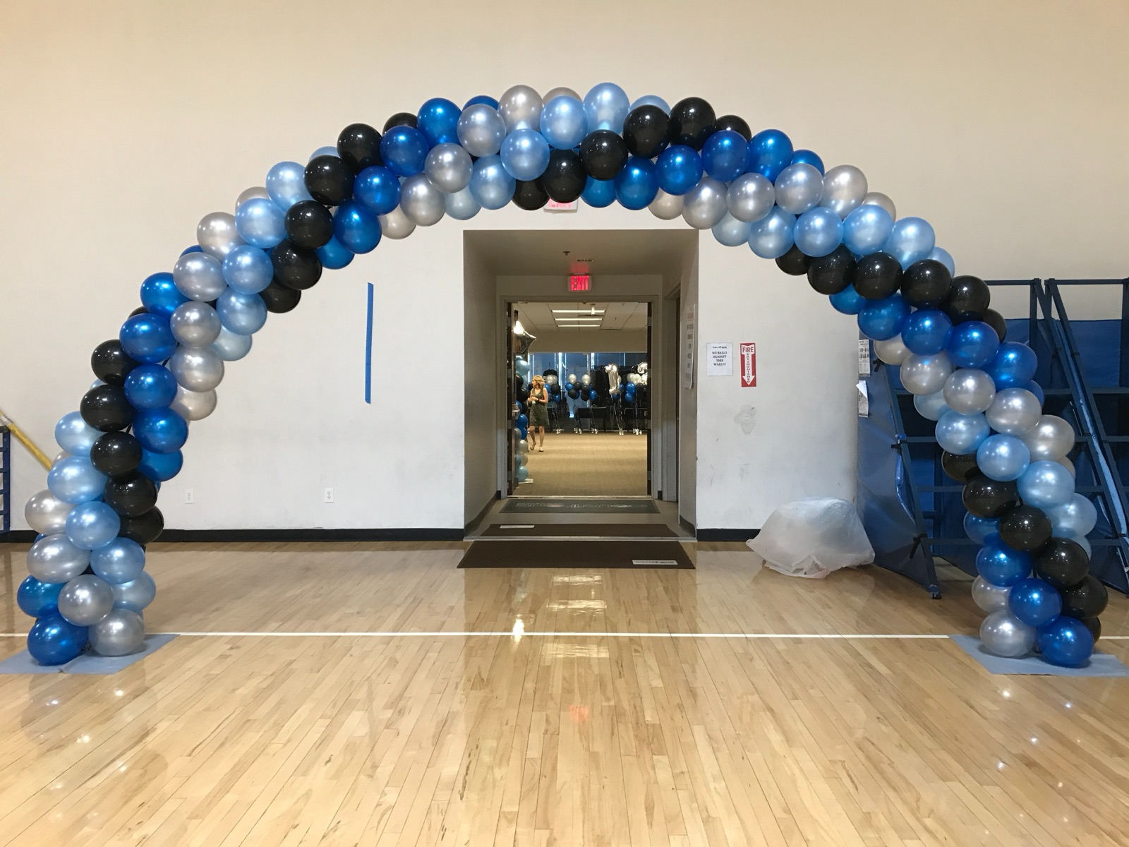 Blue and silver balloon arch spanning a hallway by AZ Party Mart