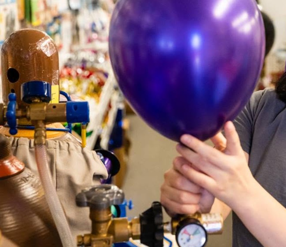 Filling a balloon with a helium tank rented from AZ Party Mart