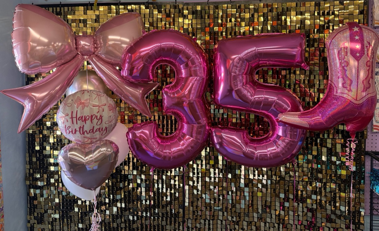 Rose gold number balloon bouquet with a bow against a gold sequin backdrop