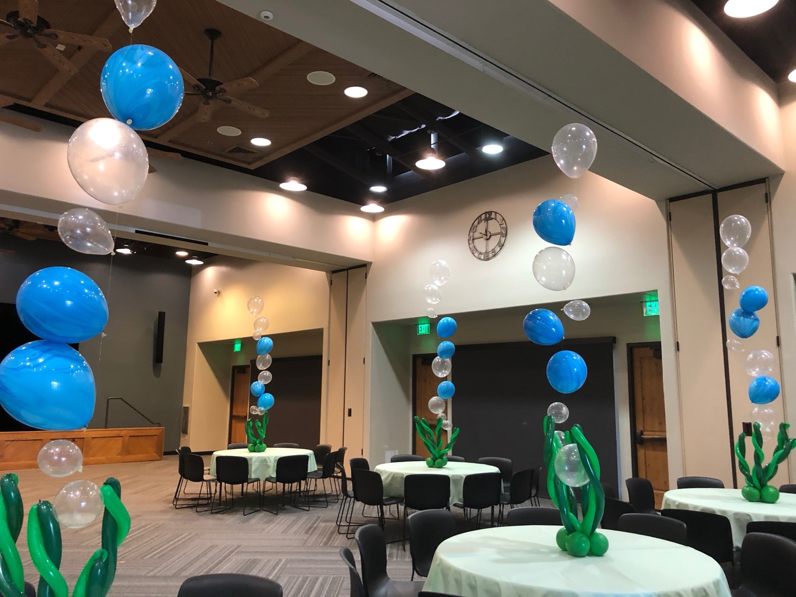 Blue and white balloon clusters and balloon cacti decorating an event hall