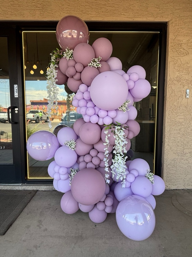 Lavender and mauve organic balloon garland cascading down a storefront doorway